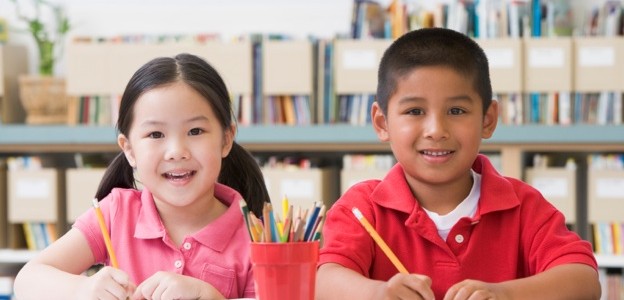 Kindergarten children sitting at desk and writing in classroom