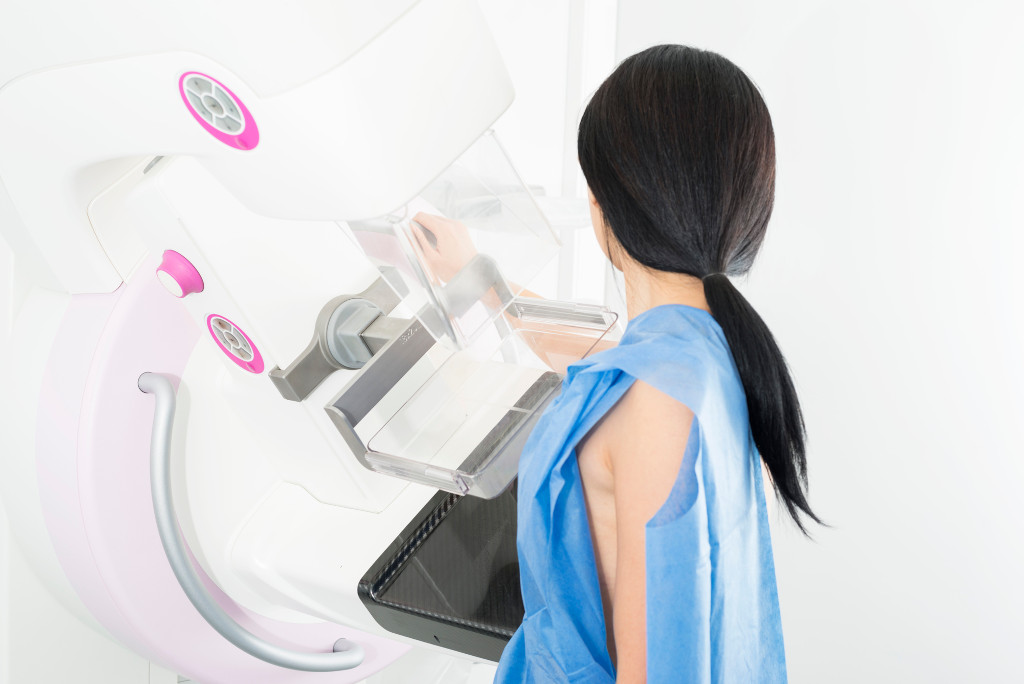 Side view of mature woman undergoing mammogram X-ray test in clinic