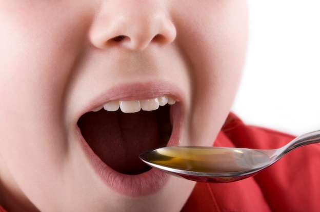Sick child taking medicine or cod liver oil