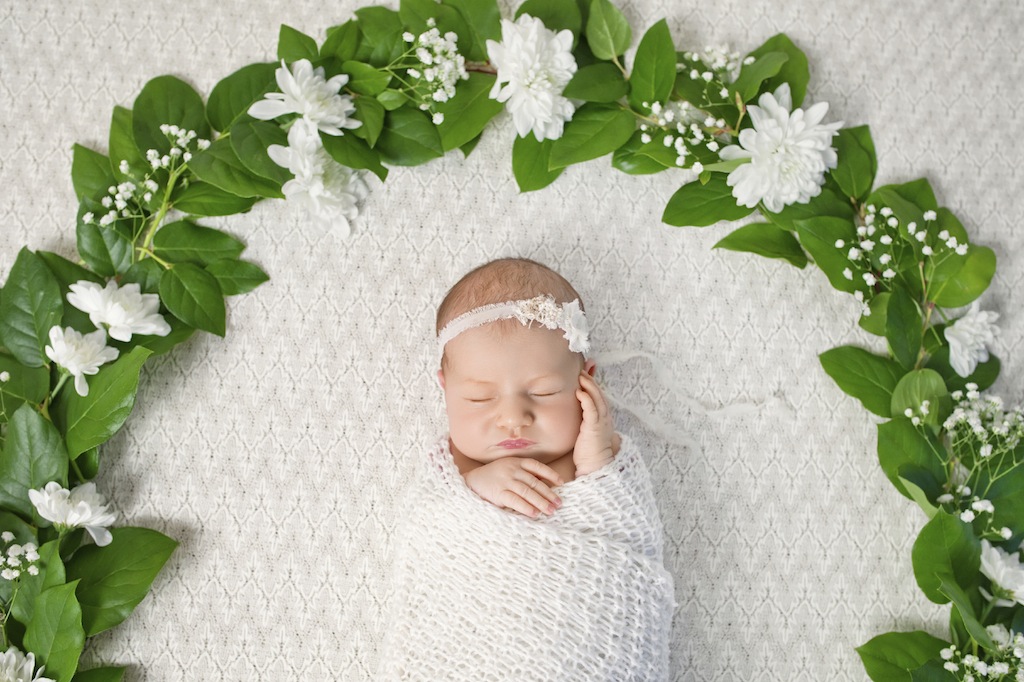 Little newborn girl 11 days, sleeps. Beautiful newborn girl and flowers
