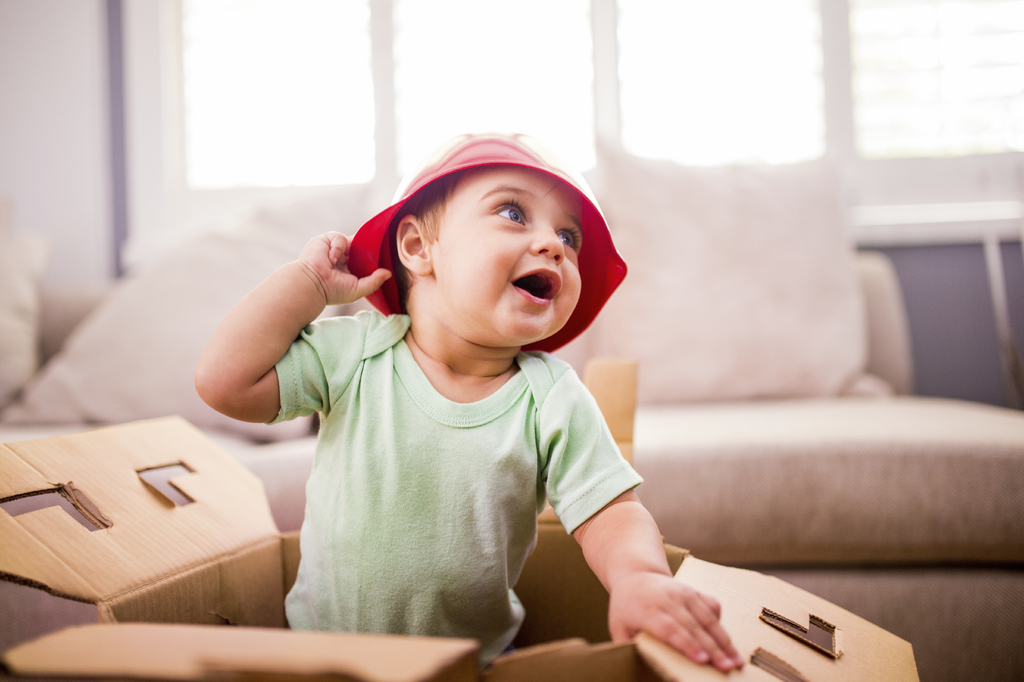Excited baby wearing a plastic bowl as a hat