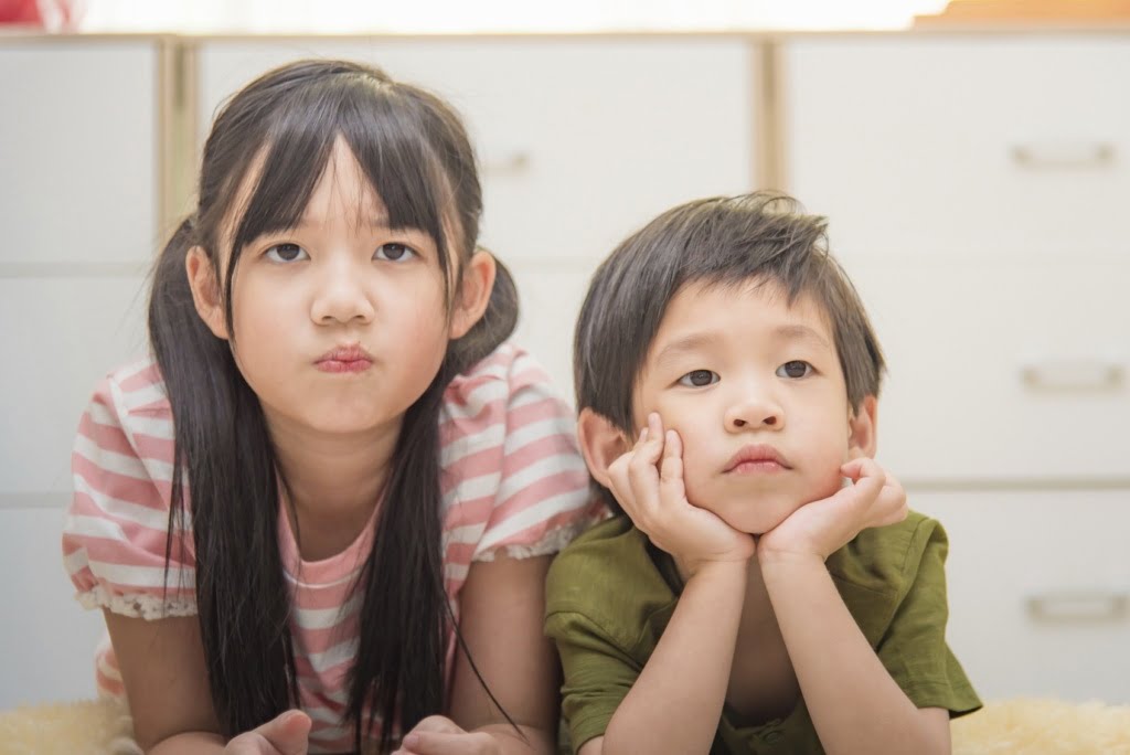 Close up of cute asian child sister and brother lying on the ground.