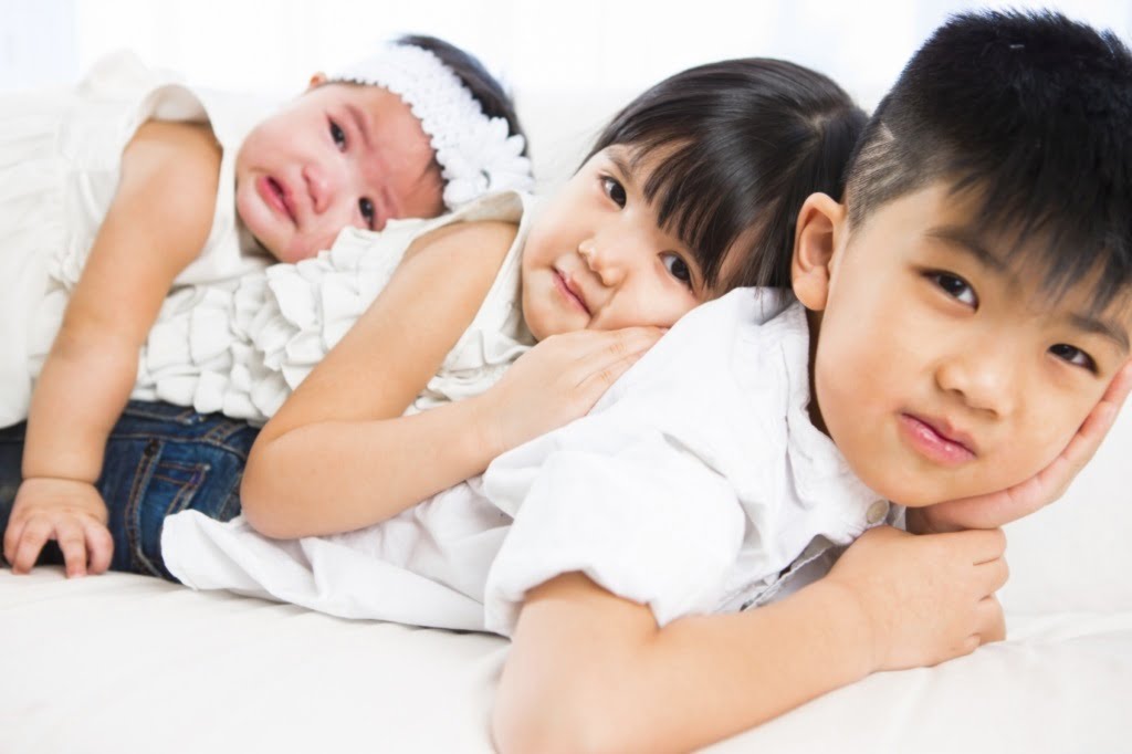 Asian sibling portrait laying on front