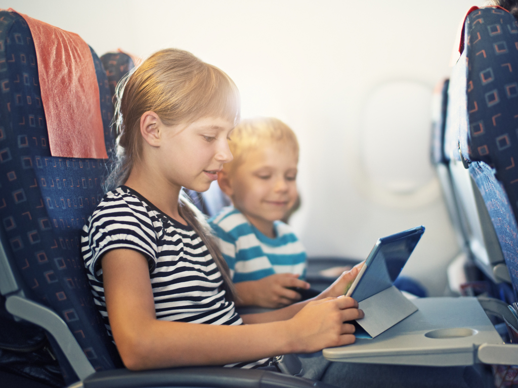 Brother and sister playing with tablet in plane