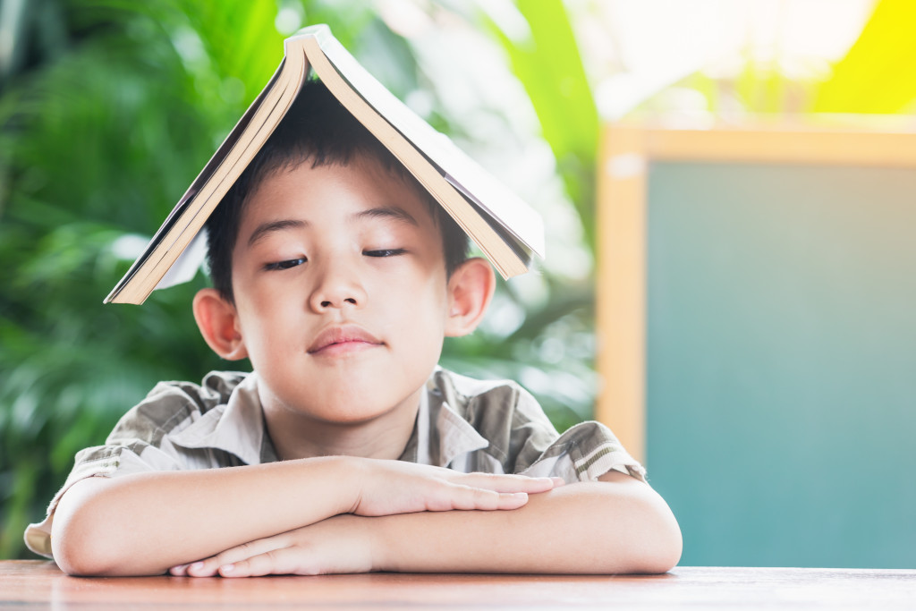 Asian little boy holding book on head