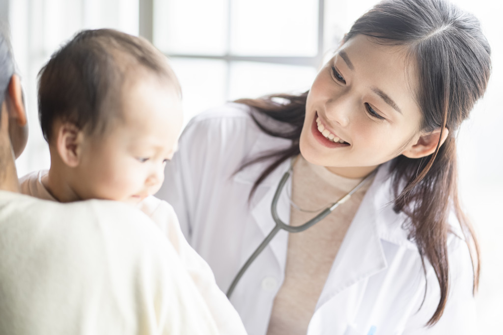 A female doctor smiles with a baby during healthcheck