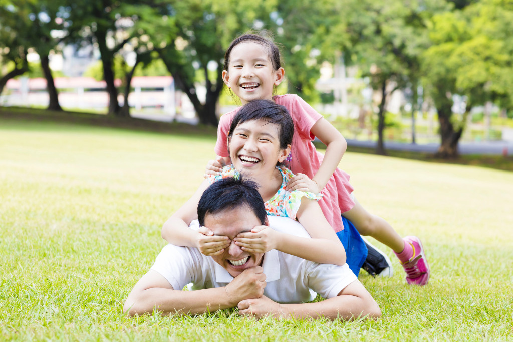 Girls playing with dad in the park on Father’s Day